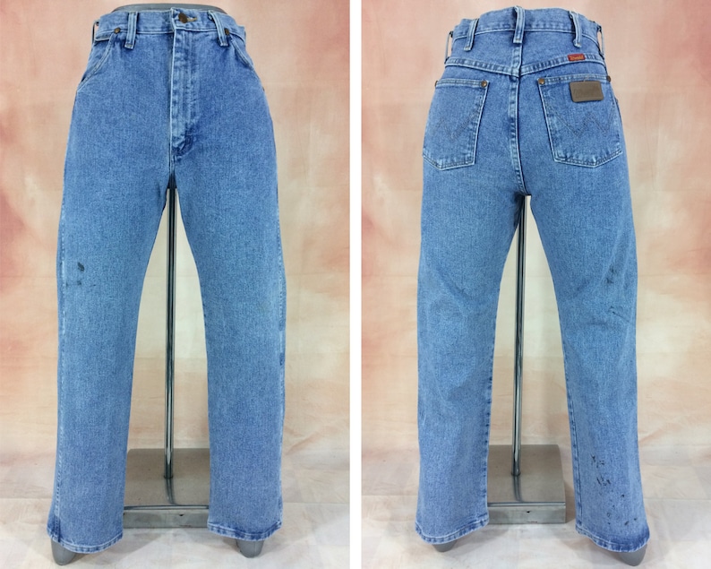 May include: A pair of light blue denim jeans with a brown leather patch on the back pocket. The jeans have a straight leg and a classic fit.