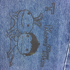 May include: A blue denim jacket with a black cartoon illustration of two figures and the text "Happy Birthday".