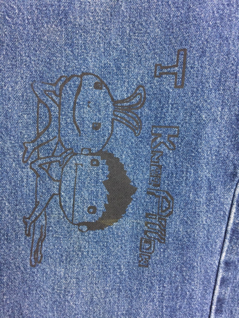 May include: A blue denim jacket with a black cartoon illustration of two figures and the text "Happy Birthday".