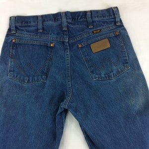 May include: A pair of blue denim jeans with a brown leather Wrangler patch on the back pocket.