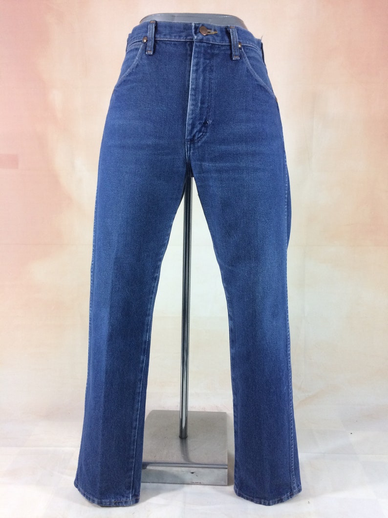 May include: Blue denim jeans with a classic five-pocket design. The jeans have a straight leg cut and a button and zipper closure. The jeans are displayed on a mannequin. The jeans are a medium wash.