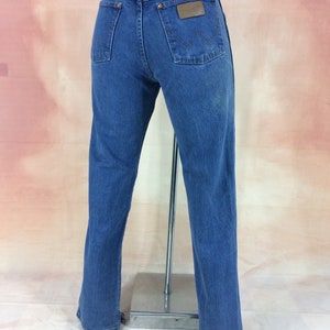 May include: A pair of blue denim jeans with a brown leather patch on the back pocket that says "Wrangler".
