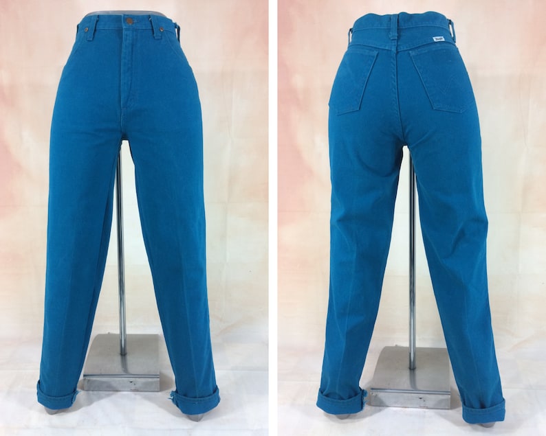 May include: A pair of high-waisted jeans in a vibrant teal blue color. The jeans have a straight leg fit and are cuffed at the bottom.