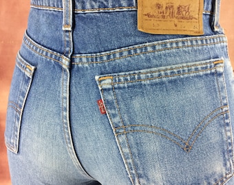 May include: Light blue denim jeans with a classic five-pocket design. Features a red Levi's tag on the back pocket and a brown leather patch. The jeans have a straight leg cut and are made of durable denim.