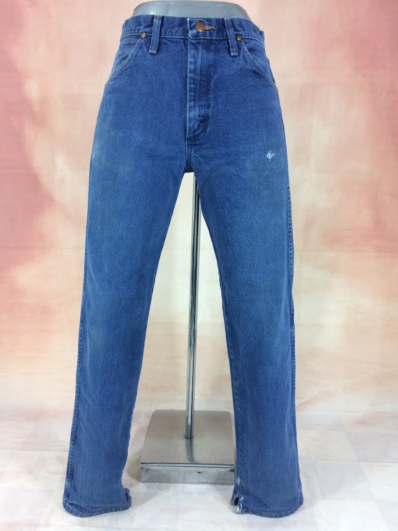 May include: A pair of blue denim jeans with a straight leg fit. The jeans have a faded look and are slightly distressed.