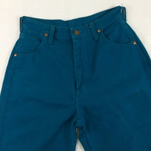 May include: Teal blue high-waisted jeans with a zipper fly and button closure.