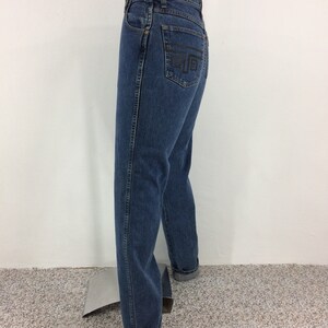 May include: A pair of blue denim jeans with a black embroidered design on the back pocket. The jeans have a high waist and a straight leg.