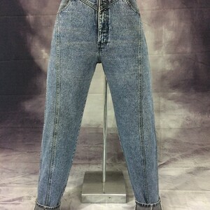 May include: Acid wash denim jeans with a high waist and a button closure. The jeans have a classic five-pocket design and a straight leg with a cuffed hem. The jeans are displayed on a mannequin.