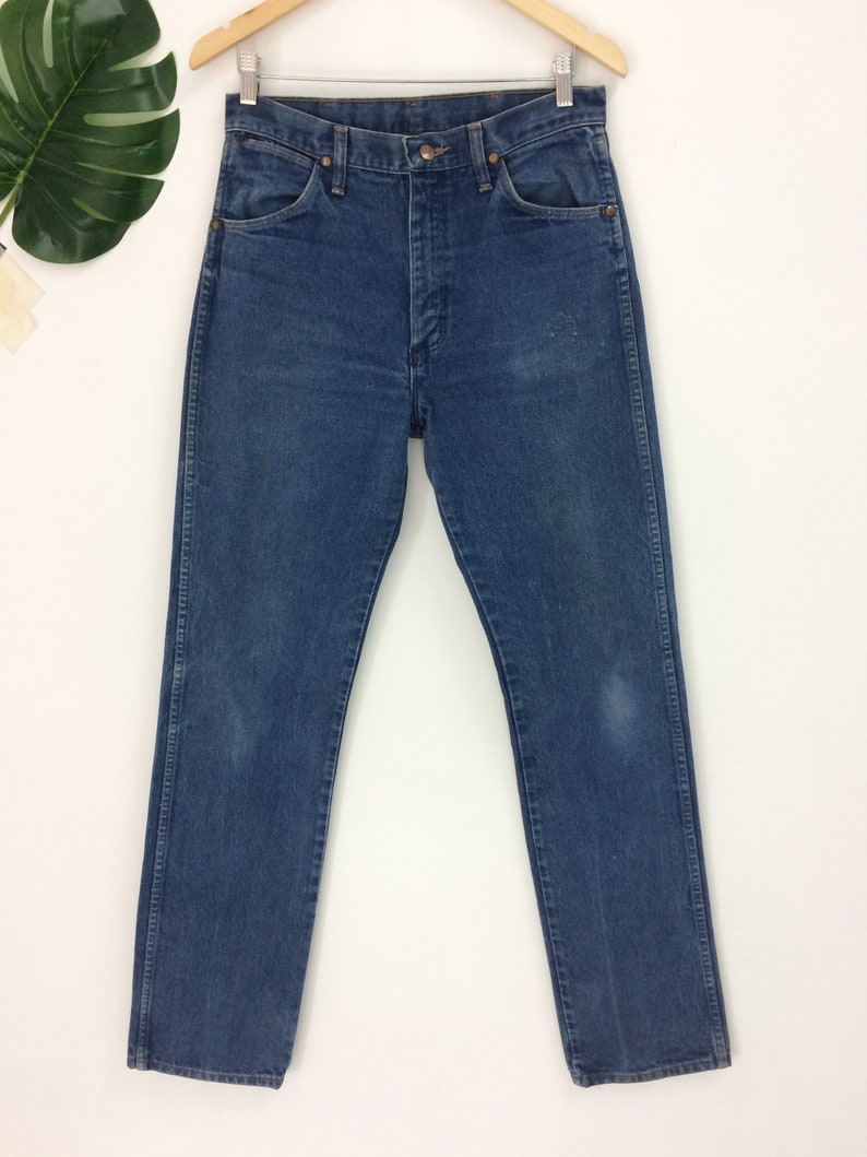 Peut inclure: Un jean bleu denim &agrave; jambe droite. Le jean a un style classique &agrave; cinq poches et une braguette &agrave; boutons.