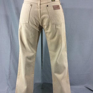 May include: A pair of light brown Wrangler jeans with a brown leather patch on the back pocket.