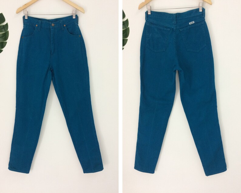 May include: A pair of high-waisted jeans in a vibrant teal blue color. The jeans have a classic straight leg fit and a button fly closure.