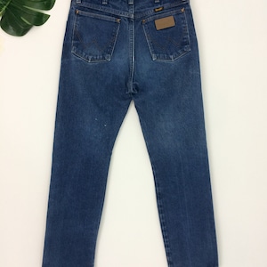 May include: A pair of blue denim jeans with a brown leather patch on the back pocket that says "Wrangler".