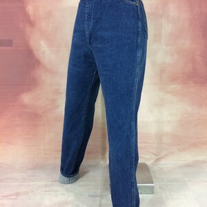 May include: Dark blue denim jeans with a high waist and straight leg. The jeans have a classic five-pocket design, a button and zipper closure, and are cuffed at the ankles. The jeans are displayed on a mannequin.