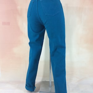 May include: Teal blue high-waisted jeans with a Wrangler label on the back pocket.