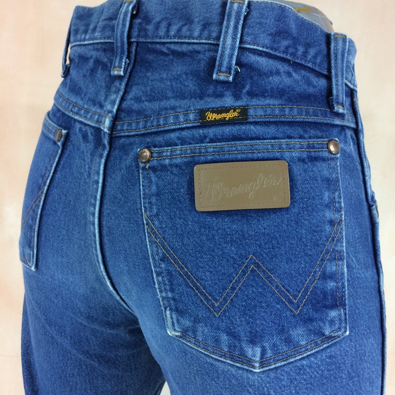 May include: A pair of blue denim jeans with a brown leather patch on the back pocket that says "Wrangler".