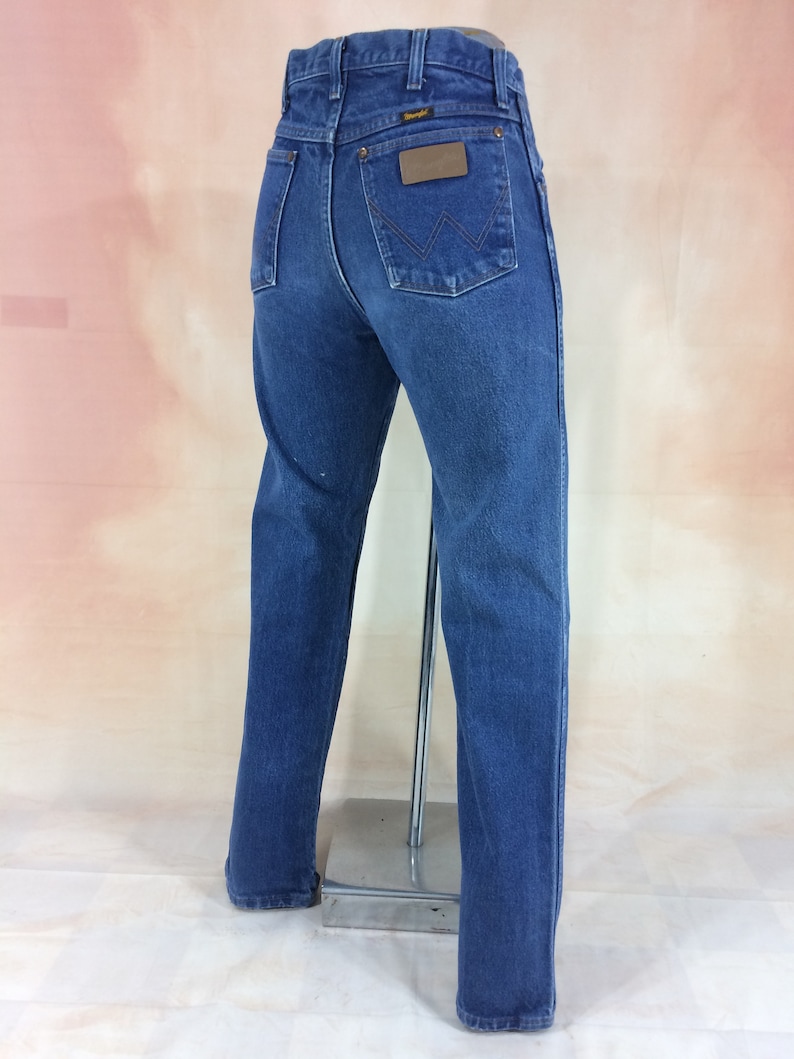 May include: A pair of blue denim jeans with a brown leather patch on the back pocket that says "Wrangler".