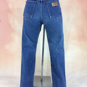 May include: A pair of blue denim jeans with a brown leather patch on the back pocket that says "Wrangler".