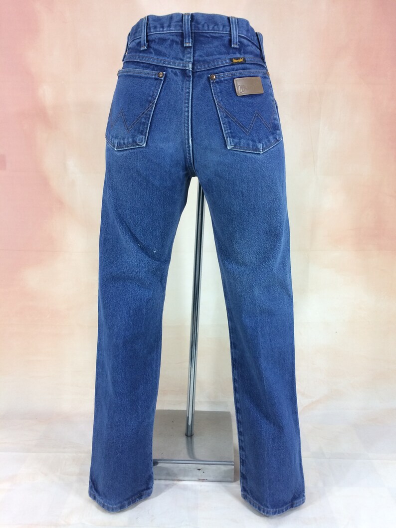 May include: A pair of blue denim jeans with a brown leather patch on the back pocket that says "Wrangler".