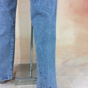 May include: A pair of light blue denim jeans with a flared leg. The jeans have a few dark spots on the fabric.