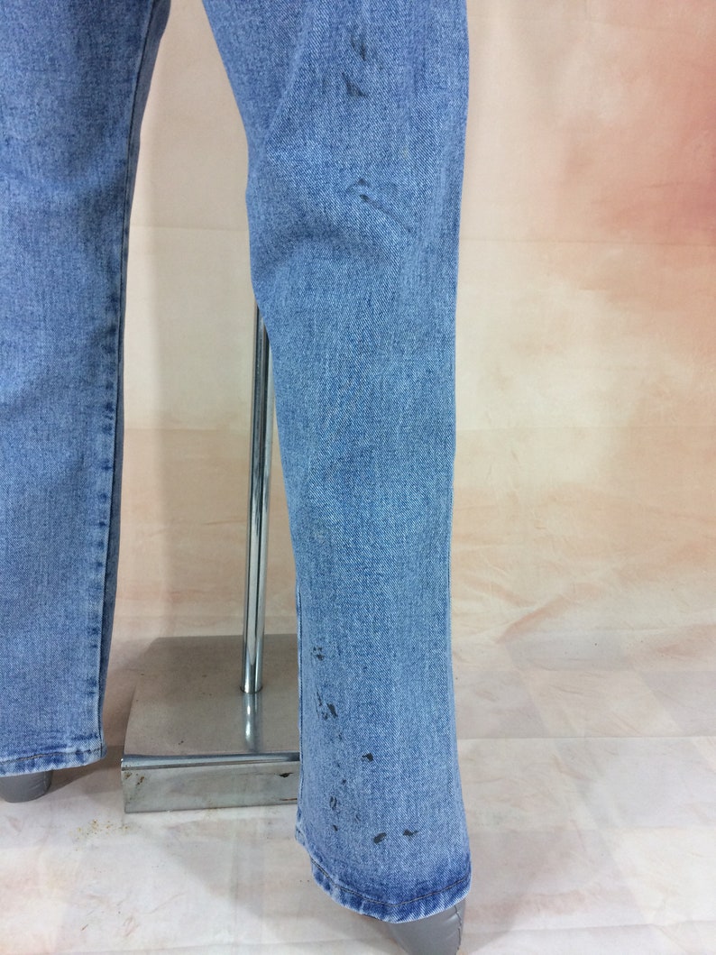 May include: A pair of light blue denim jeans with a flared leg. The jeans have a few dark spots on the fabric.