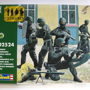 Op de afbeelding: Afbeelding op een modelbouwdoos met Duitse Commando Special Forces (KSK) soldaten in zwarte uniformen, gewapend met geweren en andere uitrusting. De doos bevat de tekst "1/72 FIGUREN" en het nummer "02524".
