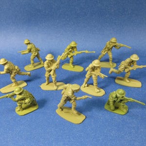 May include: A collection of olive drab plastic toy soldiers in various action poses, each holding a rifle. The figures are mounted on small, oval bases. The background is a solid blue.