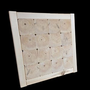 May include: A square wooden frame filled with sixteen square blocks of wood. The blocks are arranged in a grid pattern, showcasing the natural grain and circular growth rings. The frame and blocks are a light, natural wood color.