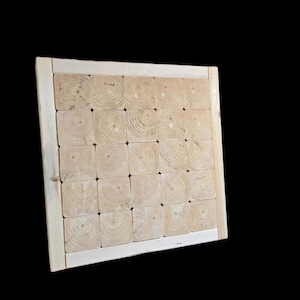 May include: A square wooden board with a grid pattern made from small, light-colored wood blocks. The blocks are arranged within a light-colored wooden frame. The wood grain is visible on the blocks.