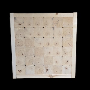 May include: A square wooden panel made from numerous small, light-colored wood blocks. The blocks are arranged in a grid pattern and framed by a light-colored wooden border. The wood grain is visible in each block.