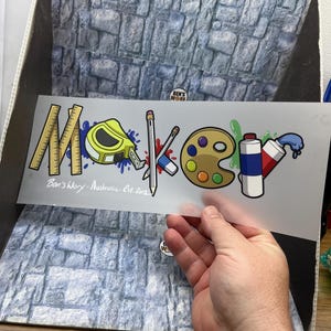 May include: A clear sticker with the word "Maker" in a colorful, cartoon style. The design incorporates a ruler, tape measure, pencil, paint palette, and paint tubes. Text at the bottom reads "Ben's Work - Australia - Est. 2015."