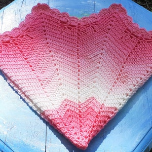 May include: A pink and white crocheted baby blanket with a scalloped edge.