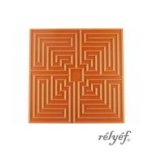 Könnte beinhalten: Eine quadratische orangefarbene Wandplatte mit einem erhabenen geometrischen Labyrinth-Muster und einem quadratischen Ausschnitt in der Mitte. Das Design besteht aus symmetrischen, ineinandergreifenden Linien. Der Text "rélyéf" steht unten rechts.