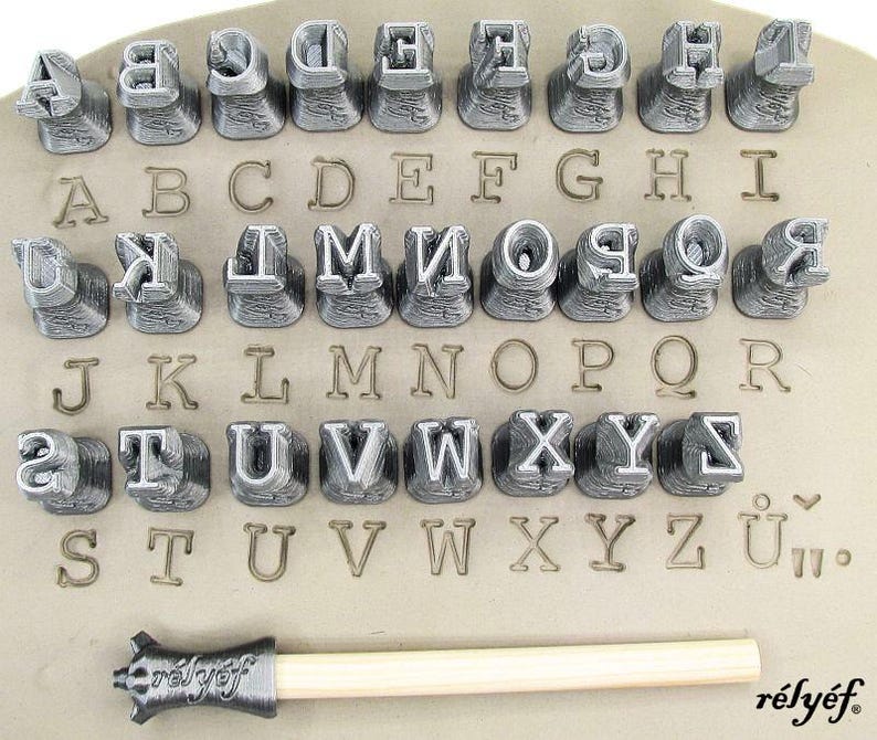 K&ouml;nnte beinhalten: Ein Satz aus Metall-Buchstaben-Stempeln zum Pr&auml;gen von Buchstaben und Zahlen auf Leder, Holz oder anderen Materialien. Die Stempel sind alphabetisch geordnet und umfassen Gro&szlig;buchstaben, Kleinbuchstaben, Zahlen und Satzzeichen. Das Set enth&auml;lt auch einen Holzgriff mit einer Metallspitze zum Pr&auml;gen.