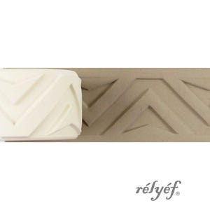 Op de afbeelding: Een witte geometrische patroonroller en zijn afdruk op een bruin oppervlak. De roller heeft een herhalend chevron-ontwerp. Het woord "rélyéf" is in scriptlettertype rechtsonder gedrukt.