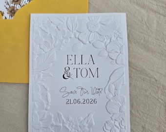 Tarjeta personalizada de anuncio de boda con diseño floral y relieve blanco.