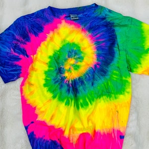 May include: A tie-dye t-shirt with a bright yellow, green, blue, and pink spiral design. The shirt has short sleeves and a crew neck.