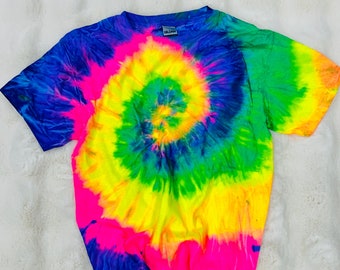 May include: A tie-dye t-shirt with a bright yellow, green, blue, and pink spiral design. The shirt has short sleeves and a crew neck.