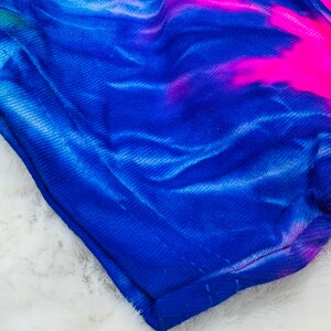 May include: A blue and pink tie-dye fabric with a textured surface.