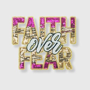 May include: A decorative sequined patch with the words "FAITH OVER FEAR". The letters are outlined in gold and filled with pink and gold sequins. The word "OVER" is in white cursive script.