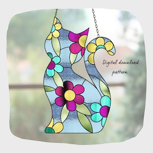 Può includere: Silhouette di gatto in vetro colorato con un motivo floreale. Il gatto è azzurro con fiori colorati nelle tonalità del rosa, giallo e verde acqua. Il testo "Digital download pattern" è sul lato destro. Il gatto è appeso a una catena.