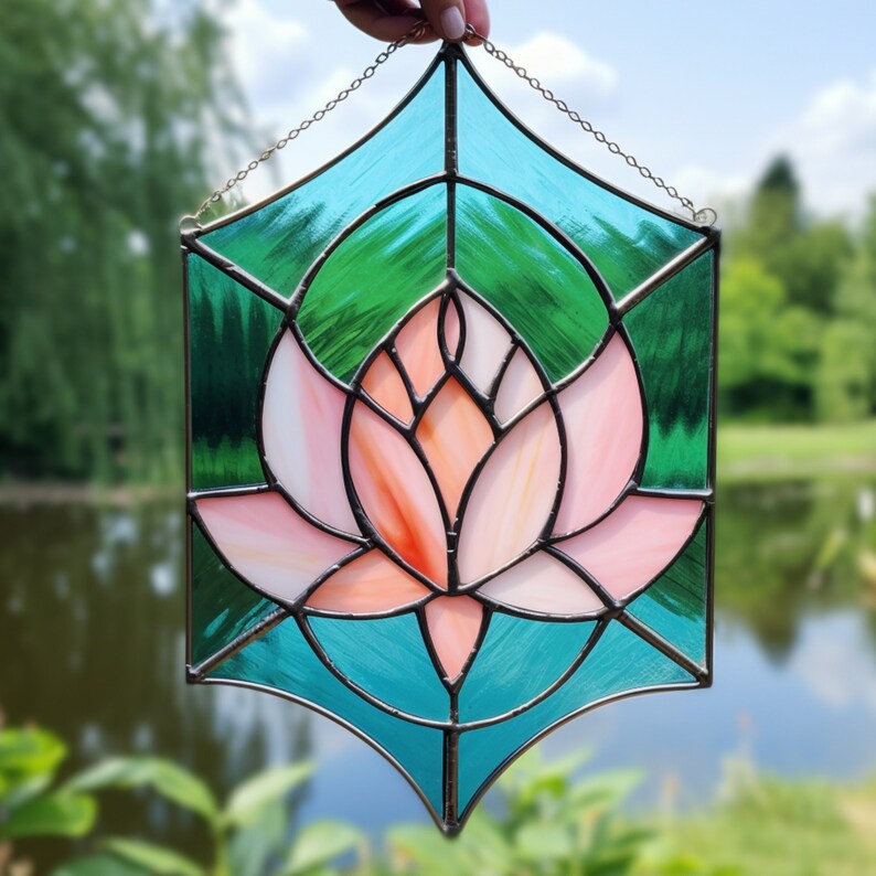 May include: A stained glass window depicting a pink lotus flower with a teal blue background. The flower is surrounded by a geometric pattern.