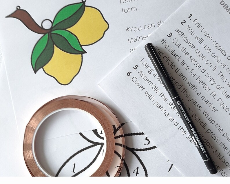 May include: A close-up of a craft project with instructions for making a stained glass lemon design. The instructions include using copper tape, a black marker, and a clear adhesive tape. The image also shows a roll of copper tape and a black marker.