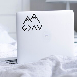 May include: Black and white sticker with a mountain range design and the text "God is greater than the highs and lows".