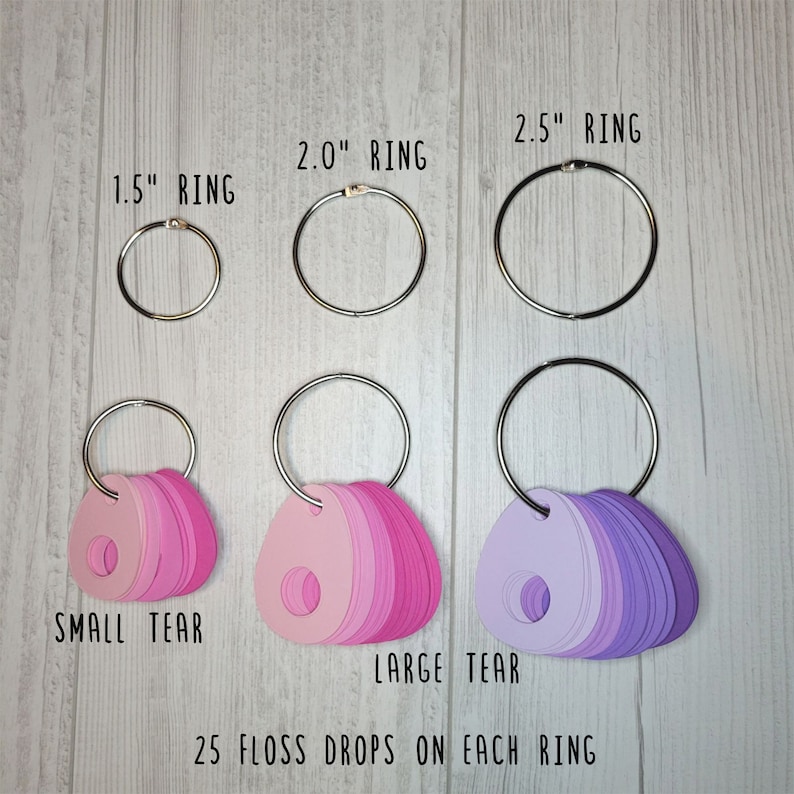 May include: A collection of floss drops in shades of pink and purple, attached to silver rings. The rings are labeled as 1.5", 2.0", and 2.5" in diameter. The text reads "SMALL TEAR", "LARGE TEAR", and "25 FLOSS DROPS ON EACH RING".