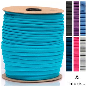 May include: A spool of turquoise blue elastic cord, wound around a cardboard core. The cord is smooth and appears to be made of a soft, stretchy material.
