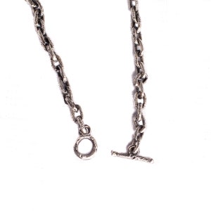 May include: A silver chain necklace with a textured finish. The necklace has a t-bar clasp and a round ring at the other end.