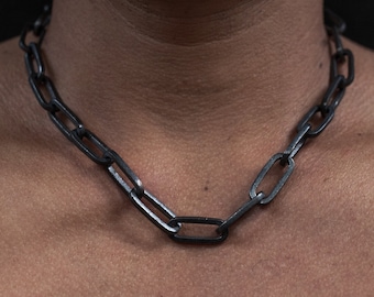Può includere: Una collana a catena nera realizzata con grandi maglie ovali.
