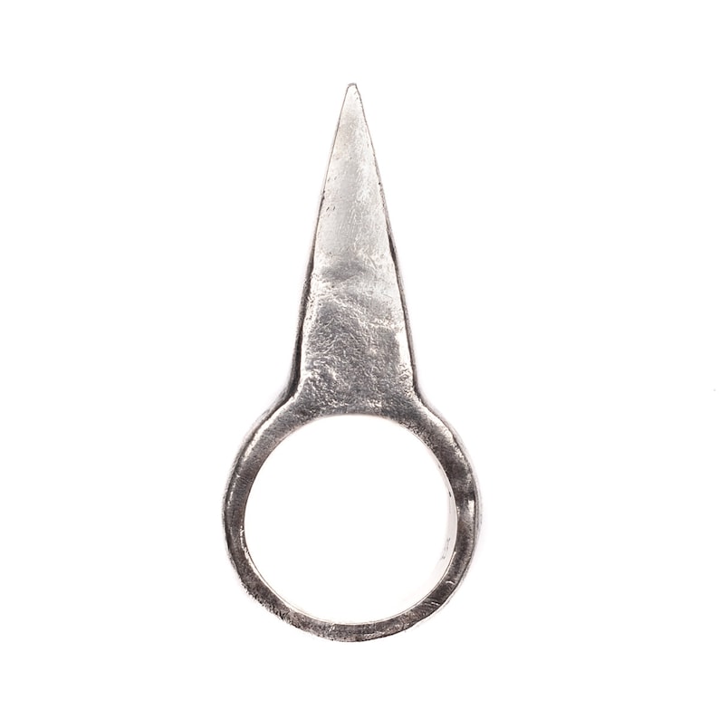 May include: A silver ring with a pointed, sharp, triangular top.
