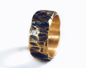 May include: A wide, textured gold band ring with a hammered finish.