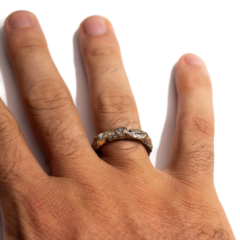 May include: A gold ring with a textured, organic design. The ring is worn on a person's finger.